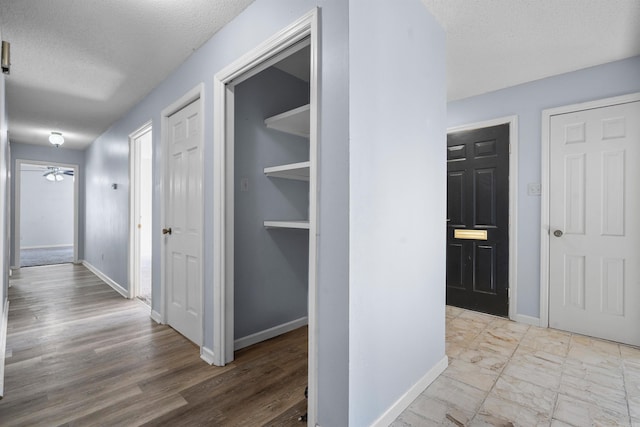 hallway with light wood-type flooring and a textured ceiling