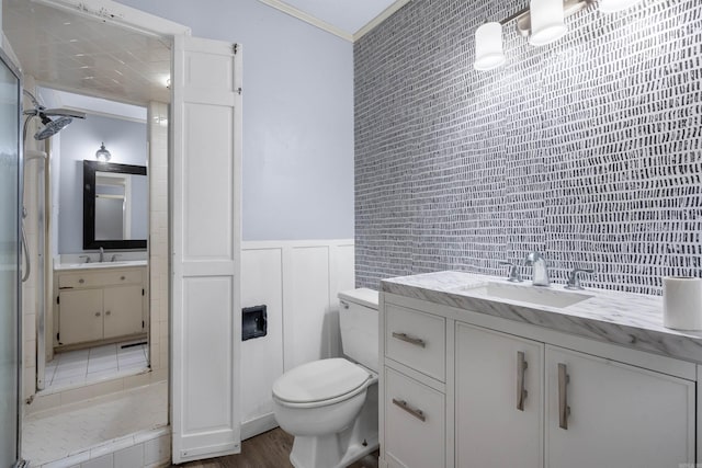 bathroom with backsplash, toilet, vanity, ornamental molding, and tile walls