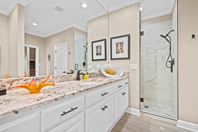 bathroom with wood-type flooring, ornamental molding, an enclosed shower, and vanity