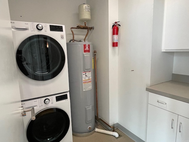 clothes washing area featuring stacked washer and dryer, tile patterned floors, cabinets, and water heater