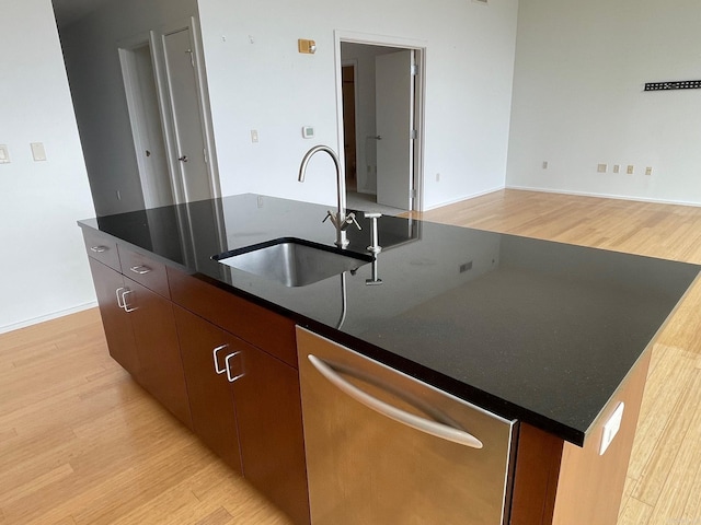 kitchen featuring sink, dishwasher, light wood-type flooring, and an island with sink