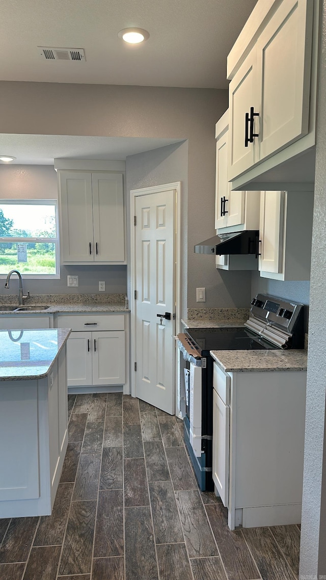 kitchen with electric stove, sink, extractor fan, light stone countertops, and white cabinets