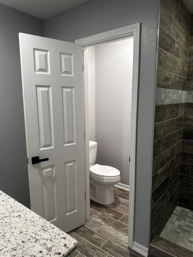 bathroom with tiled shower and toilet