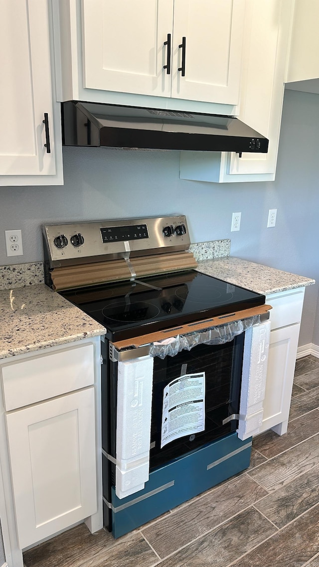 kitchen featuring white cabinetry, stainless steel electric range oven, and extractor fan