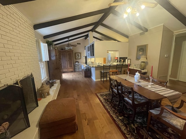 dining area with ceiling fan, vaulted ceiling with beams, wood-type flooring, a fireplace, and brick wall