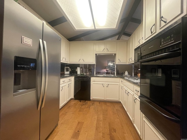 kitchen with vaulted ceiling, sink, white cabinets, black appliances, and light hardwood / wood-style flooring