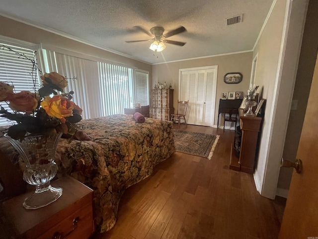 bedroom with wood-type flooring, ornamental molding, ceiling fan, a textured ceiling, and a closet