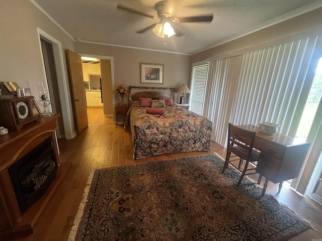 bedroom featuring hardwood / wood-style flooring, ornamental molding, ceiling fan, and a textured ceiling