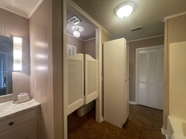 bathroom with vanity, ornamental molding, a bathing tub, and a textured ceiling