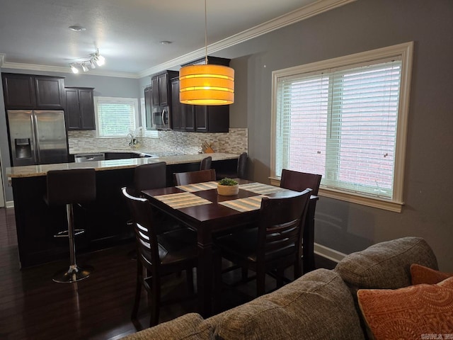 dining area featuring sink, crown molding, and dark wood-type flooring