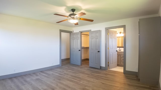 unfurnished bedroom featuring hardwood / wood-style flooring, ensuite bath, a closet, and a spacious closet