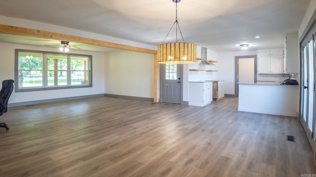 kitchen featuring white cabinetry, plenty of natural light, wood-type flooring, and pendant lighting