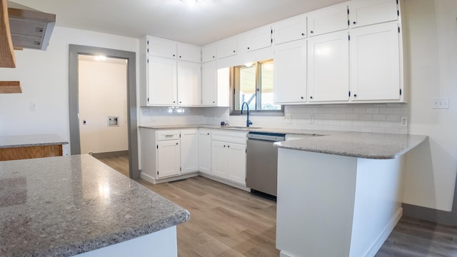 kitchen featuring stainless steel dishwasher, kitchen peninsula, light stone countertops, and white cabinets