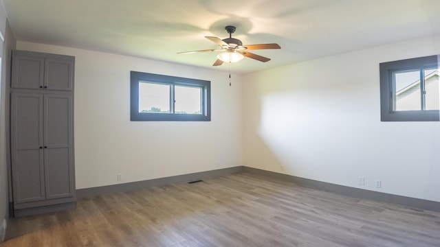 spare room with ceiling fan, a healthy amount of sunlight, and light wood-type flooring