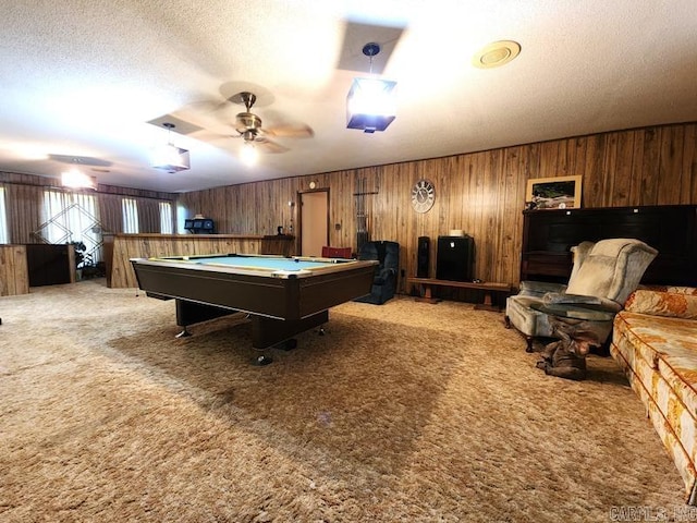 game room featuring wooden walls, a textured ceiling, pool table, ceiling fan, and carpet floors