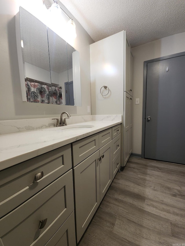 bathroom with hardwood / wood-style flooring, a textured ceiling, and vanity