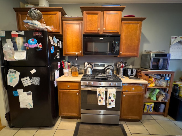 kitchen featuring brown cabinets, black appliances, light tile patterned floors, and light countertops