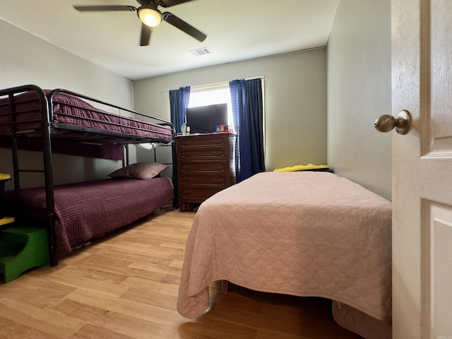 bedroom featuring wood finished floors, visible vents, and a ceiling fan