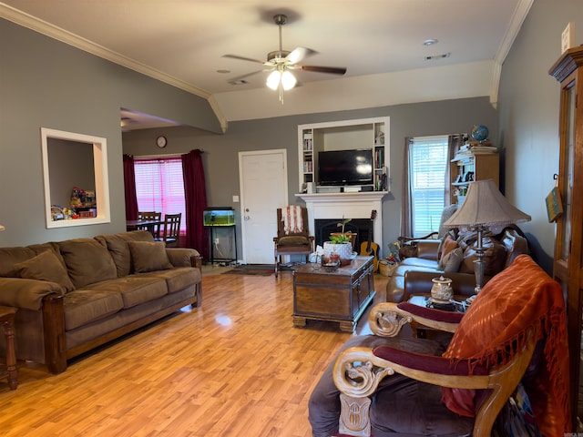 living room with light wood finished floors, crown molding, a fireplace, and a wealth of natural light