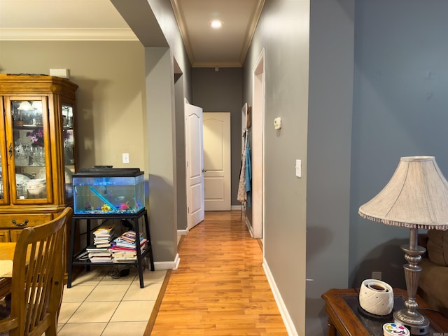 corridor with baseboards, light wood finished floors, and crown molding