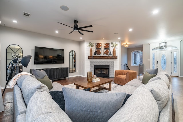 living room featuring ceiling fan, dark hardwood / wood-style flooring, and a brick fireplace