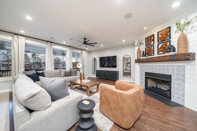 living room featuring hardwood / wood-style floors, a tile fireplace, and ceiling fan