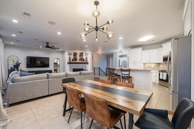 tiled dining area with ceiling fan with notable chandelier