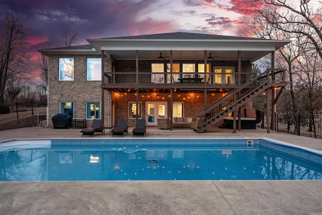 back house at dusk with a patio area, a fenced in pool, and ceiling fan