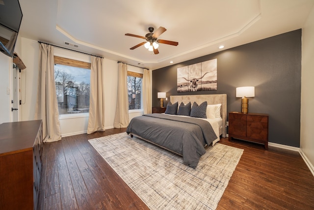 bedroom featuring dark hardwood / wood-style floors, ceiling fan, and a tray ceiling