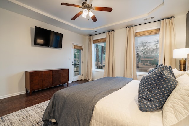 bedroom with access to exterior, dark hardwood / wood-style floors, a raised ceiling, and ceiling fan