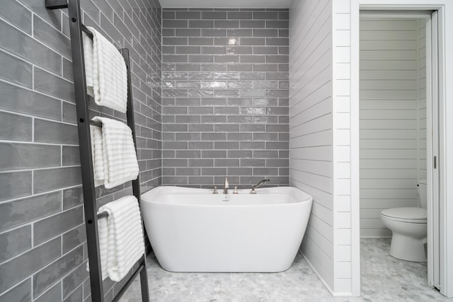 bathroom with tile walls, a tub, and toilet