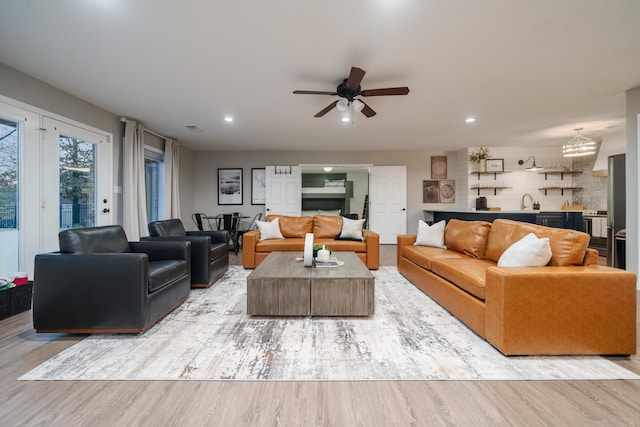 living room featuring ceiling fan, sink, and light hardwood / wood-style flooring