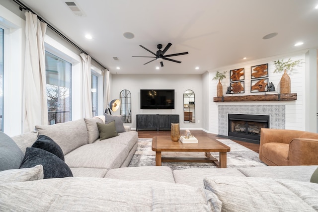 living room featuring hardwood / wood-style flooring, a tile fireplace, and ceiling fan