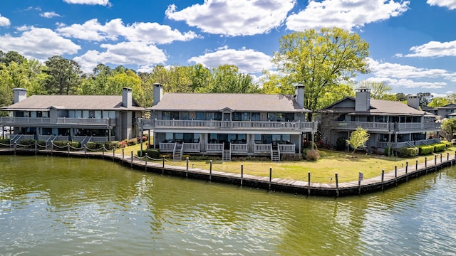 rear view of house featuring a water view and a yard