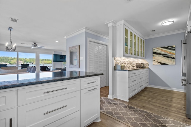 kitchen featuring white cabinetry, glass insert cabinets, tasteful backsplash, and decorative light fixtures