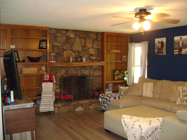 living room featuring a stone fireplace, wood-type flooring, a textured ceiling, and ceiling fan