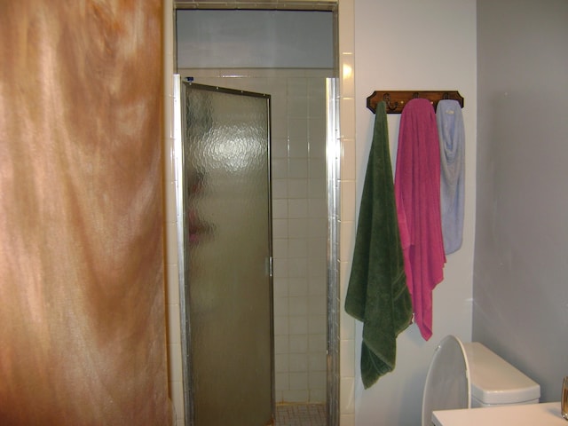 bathroom with a shower with door and toilet