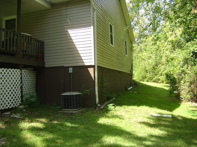 view of property exterior featuring central air condition unit, a deck, and a lawn