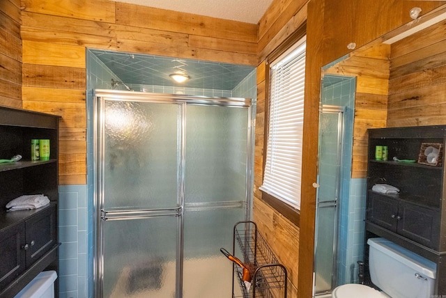 bathroom featuring wood walls, a shower with shower door, and toilet