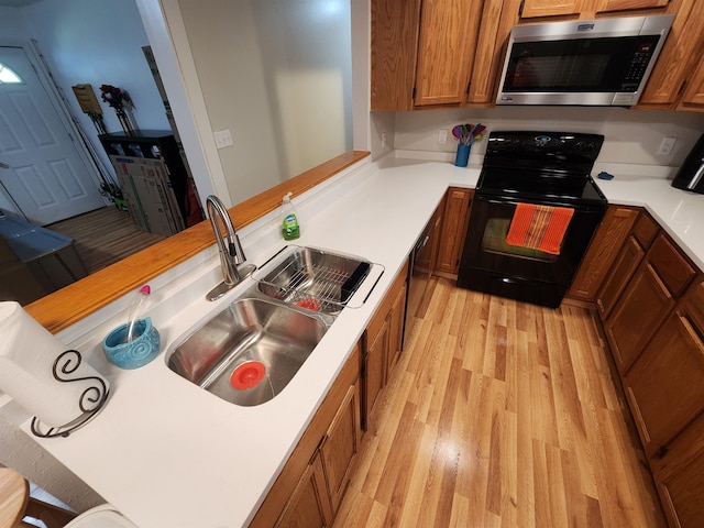 kitchen featuring sink, light hardwood / wood-style flooring, black appliances, and kitchen peninsula