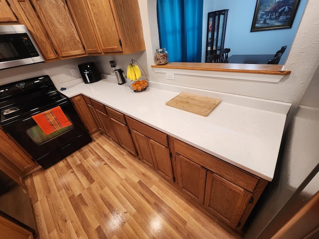 kitchen featuring kitchen peninsula, light wood-type flooring, and black range with electric cooktop