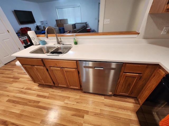 kitchen featuring dishwasher, sink, kitchen peninsula, and light hardwood / wood-style flooring