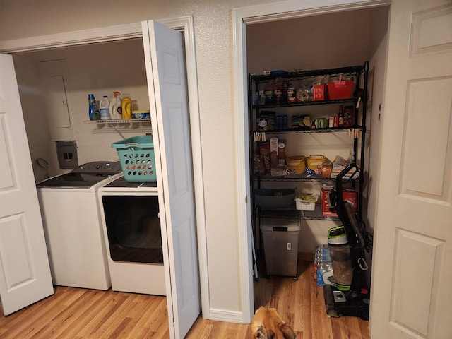 laundry room featuring electric panel, separate washer and dryer, and light wood-type flooring