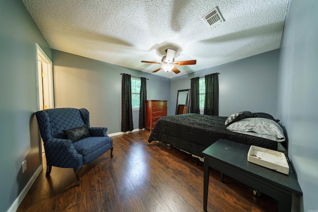 bedroom featuring dark hardwood / wood-style flooring, multiple windows, a textured ceiling, and ceiling fan