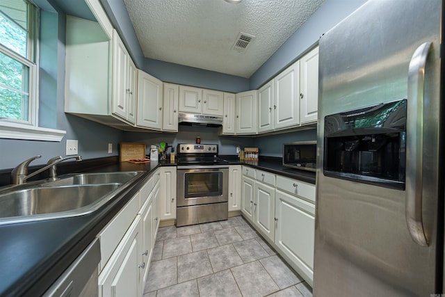 kitchen with white cabinetry, extractor fan, appliances with stainless steel finishes, a textured ceiling, and light tile patterned floors