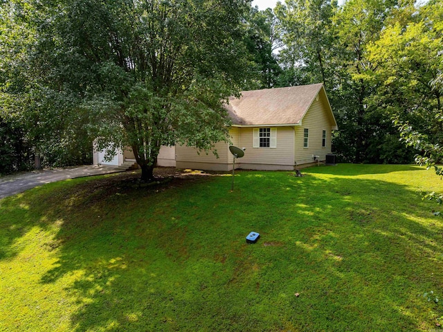 exterior space featuring a garage, central AC unit, and a front lawn