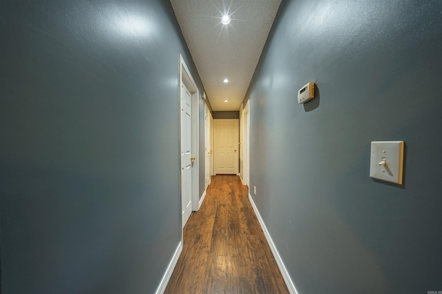 corridor with a textured ceiling and dark wood-type flooring