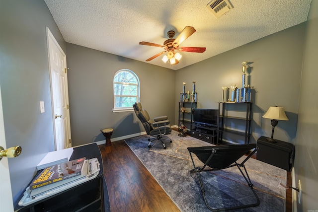 interior space featuring dark hardwood / wood-style floors, ceiling fan, and a textured ceiling