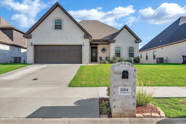 french country inspired facade featuring a garage, central AC, and a front lawn