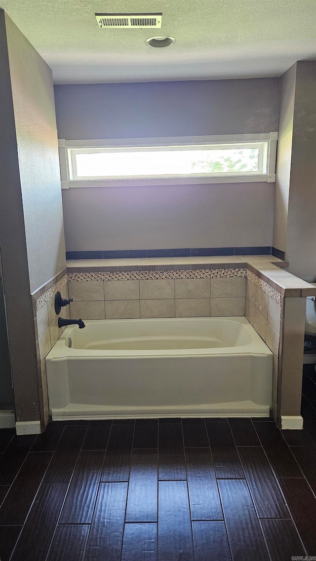 bathroom with a washtub, a textured ceiling, and plenty of natural light